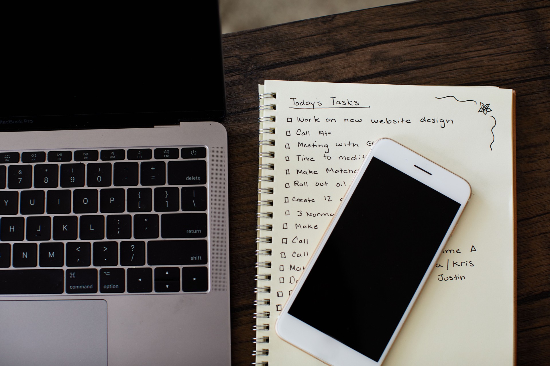 Laptop, cellphone and notebook with a to do list sitting on a wood table
